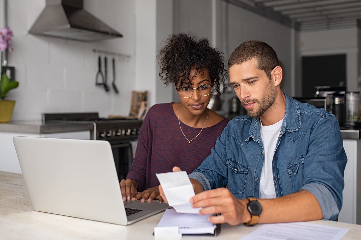 Stel bekijkt samen een rekening achter de laptop in de keuken