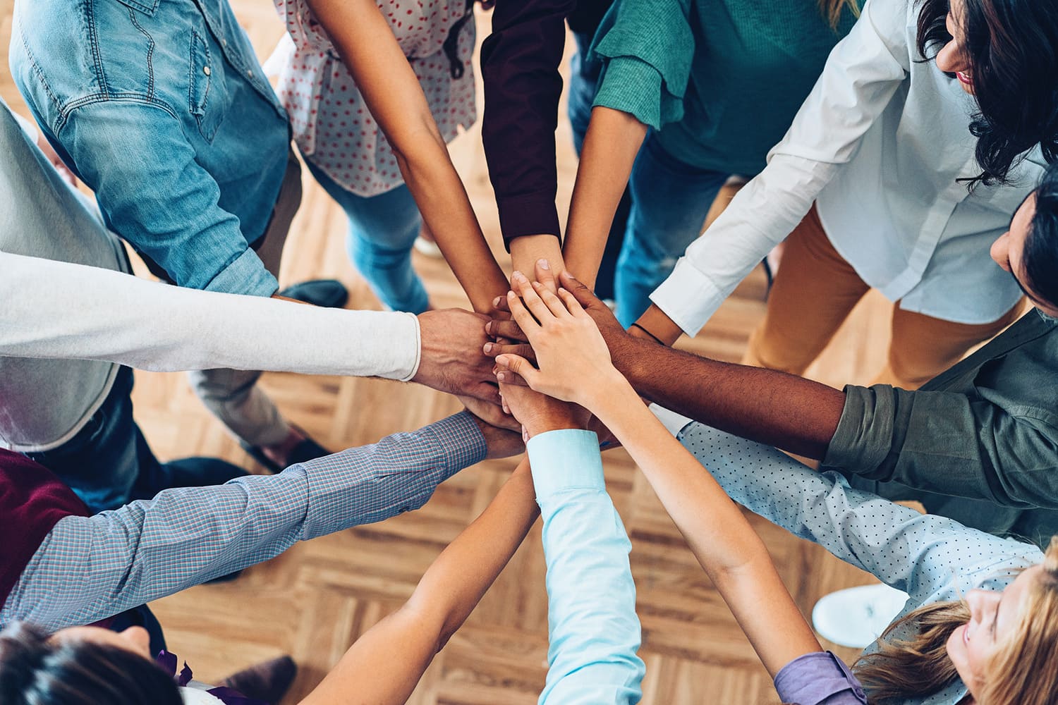 Groep mensen legt de handen op elkaar als teken van samenwerking, passend bij het motto Inzicht op uitzicht